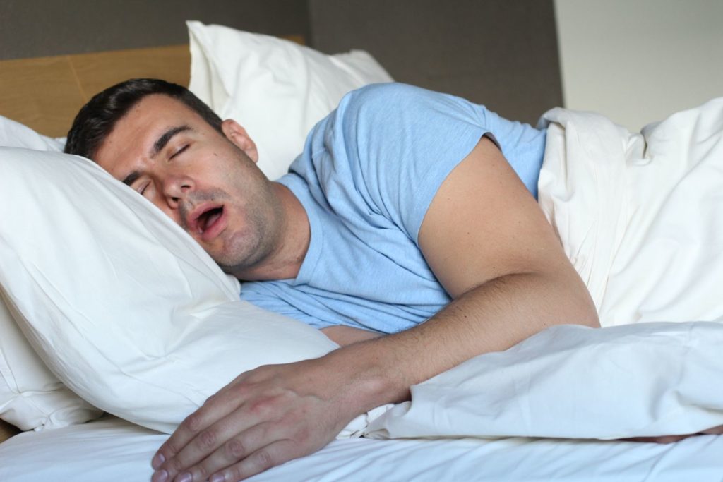 man sleeping in bed with mouth open snoring sleep apnea restorative dentistry dentist in Acton Massachusetts 